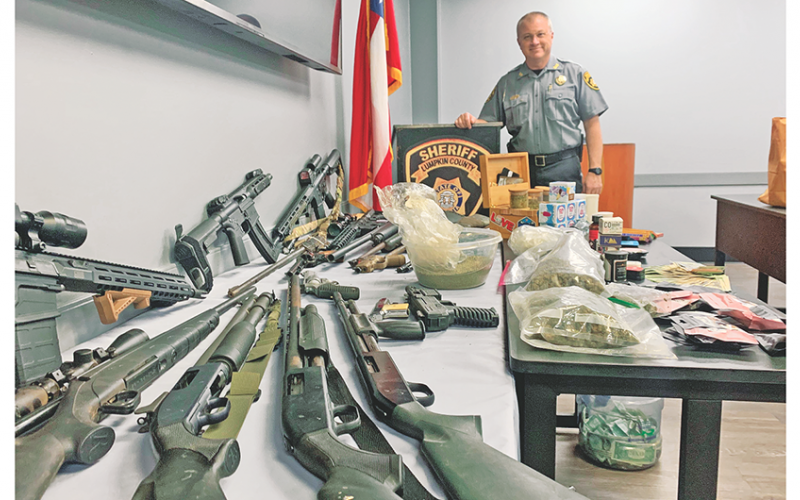Deputies and drug agents confiscated numerous firearms, a reported three pounds of marijuana, and a stash of cash from a Pecks Road residence last week.