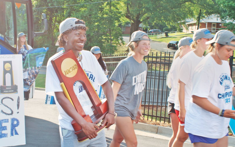 Reacting to the crowd of fans who had gathered in Dahlonega, UNG outfielder Mariah Wicker proudly holds the NCAA Division II Softball National Championship trophy as the Nighthawks return home. Once the bus arrived from Chattanooga, the team was enthusiastically greeted at their home stadium a few hours after winning the title. (photo by Keith Murden / The Nugget)