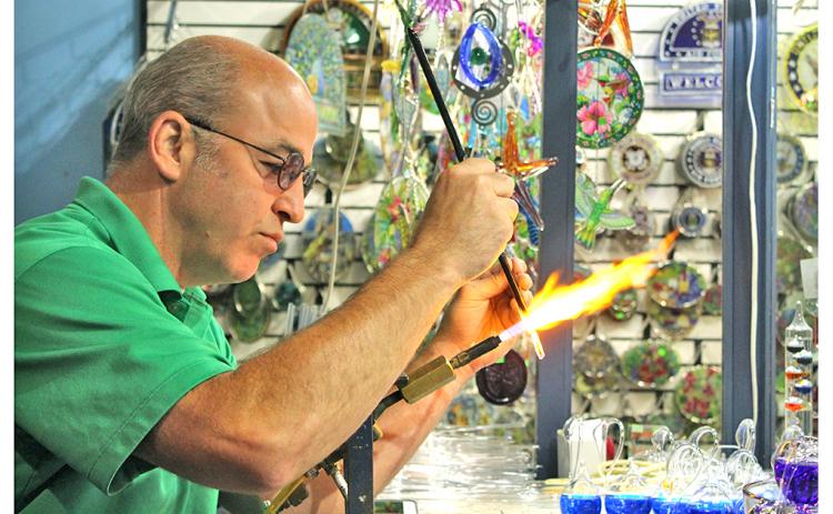 The Glassblowing Shop owner Chris Kennedy, a fourth generation glassblower, works effortlessly to combine two glass rods together for an order of icicle Christmas ornaments. This story is one of many regional features in the new edition of The Mountain Traveler magazine.