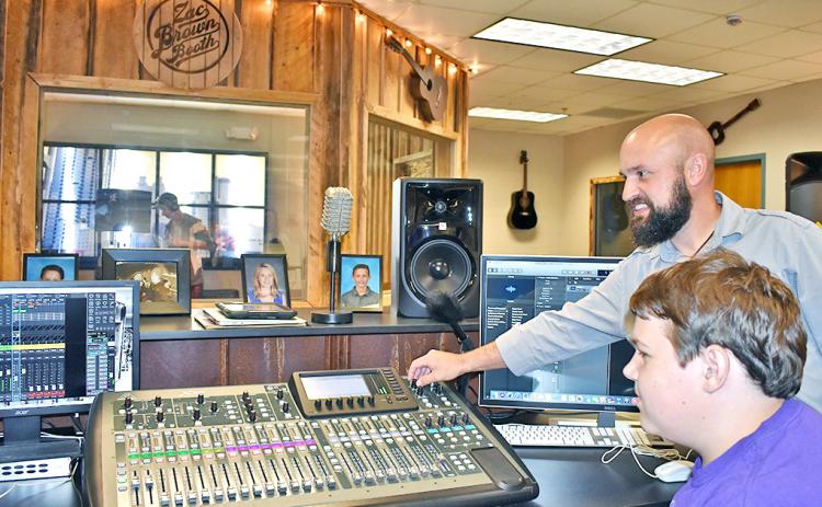 Music teacher Radford Windham shows student Brendan Diehl some of the many functions of a soundboard, purchased with money donated by Mike and Lynn Cottrell.