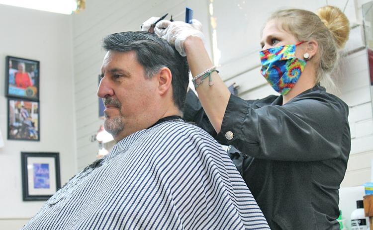 Mark Evans arrived early on Monday morning to get his first post-quarantine haircut at Woody's Barbershop. Mandi Borland was one of only two barbers to work the first day the barbershop was re-opened.