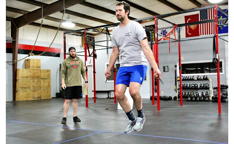 Jordan Meeks jumps rope during a workout at CrossFit Dahlonega as trainer and gym owner Thomas Coggins oversees the session.