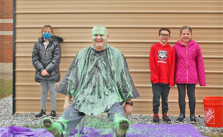 Long Branch SRO Nick Parrish was slimed in celebration of exceeding the school's original fundraising goal, much to the pleasure of LBES students (from left) Ellie Flynt, Micah Smith and Briley Seabolt.