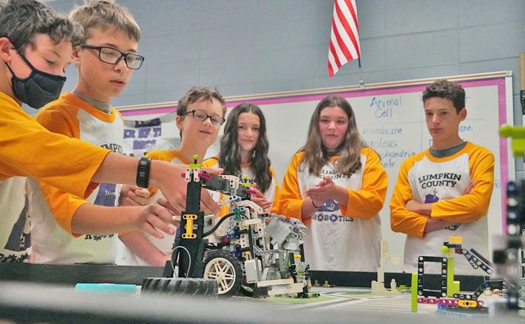 The members of the LCMS LEGO's team watch as Mathieu Weber (left) makes adjustments to the team's robot as it completes tasks as it did when the team won the FIRST LEGO League Tennessee Valley/North Georgia Region Championship in April.