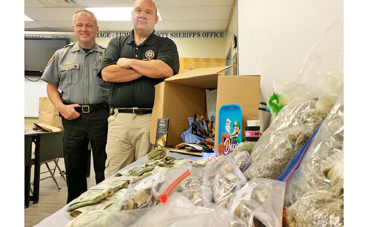 Sheriff Stacy Jarrard and Captain Marcus Sewell stand beside a table full of evidence confiscated from a recent drug bust.