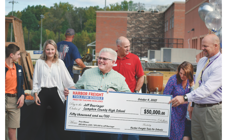 Lumpkin County High School teacher Jeff Bearinger receives a large $50,000 check from Principal Billy Kirk and Harbor Freight Regional Manager Lauren Gomez.