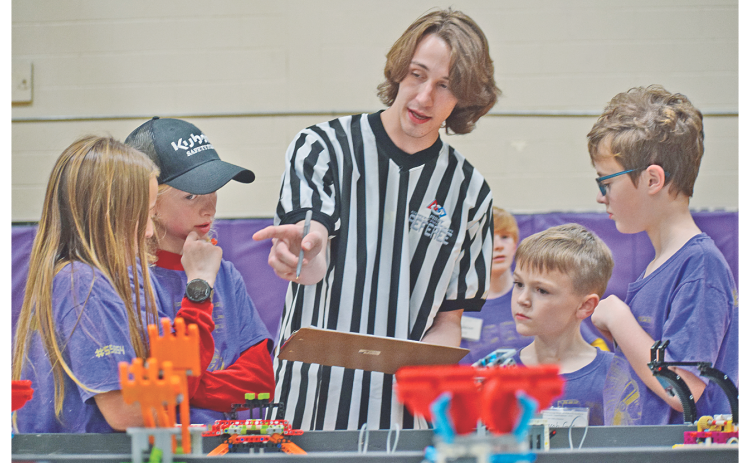 Members of the Bright Chickens of Lumpkin County Elementary School, from left, Chloe Fulton, Liam Alhadeff, Jacob Gee and Jacob Giles gather around First LEGO League referee Liam Orton as he explains the scoring process at Saturday’s competition.