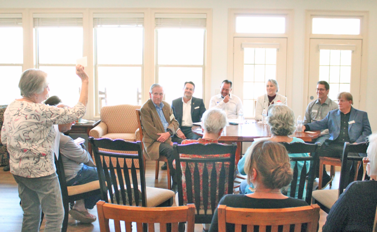 Summit Forum moderator Mary Lasris holds up a time card showing 30 seconds remaining. Seated at the table (from left) are Dahlonega City Council candidates Tom Gordineer, Lance Bagley, James Guy, Melanie Dunlap, Dan Brown and Johnny Ariemma.