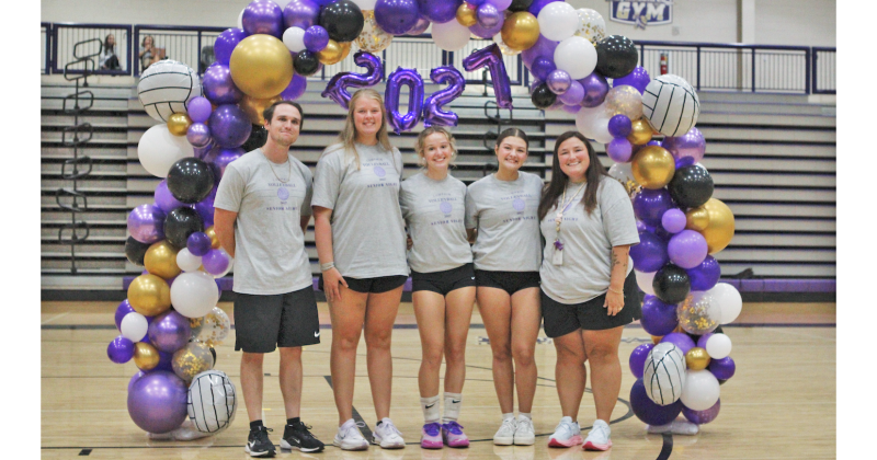 Senior players Lena Timmons (center) and Marley Rodriguez (center right) celebrate Senior Night surrounded by their coaches.
