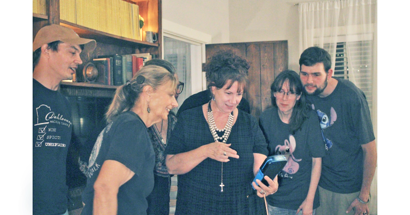 Attendee Kim Pyron holds the Para4ce Polterscript Device during a local paranormal investigation as (from left) Dahlonega Walking Tours co-owners Jeremy Sharp and Penny Sharp look on with their guests.