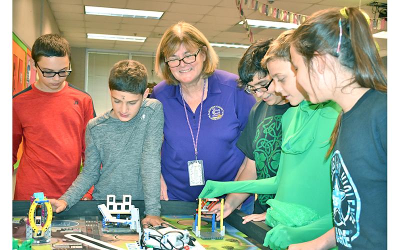 Lumpkin County’s School System Teacher of the Year, Tori Jones, oversees student members of an after-school group doing what Jones believes to be the key to education—hands-on learning. They are members of the Middle School’s FIRST LEGO League Team working (on Halloween) to build robots to accomplish a real-world task. From left are Jon Gooby, Samuel Fuerstenberg, Jones, Cameron Allison, Nathan Berzack and KayLeigh Zahn. The students will compete with other FIRST LEGO League teams Nov. 23—their first year t