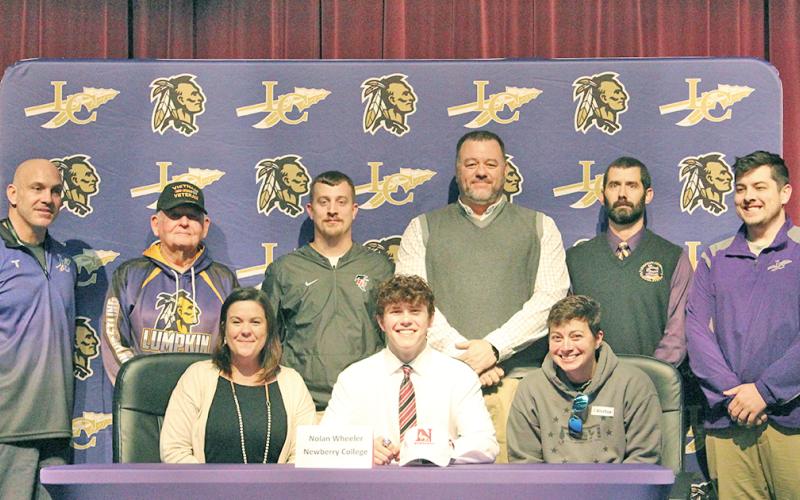 Nolan Wheeler celebrates signing with Newberry College at the LCHS auditorium. Pictured (back row, L to R): LCHS head wrestling coach Sean Hage, LCHS assistant wrestling coach Ed Wright, former LCHS assistant wrestling coach Kris Martin, former LCHS head wrestling coach Brian Matthews, former LCHS assistant coach Sean Mullins and former LCHS assistant wrestling coach Will Mayfield. (Front row): Wheeler’s mother Heather Wheeler, Wheeler and Wheeler’s bonus mom Rhonda Bass.