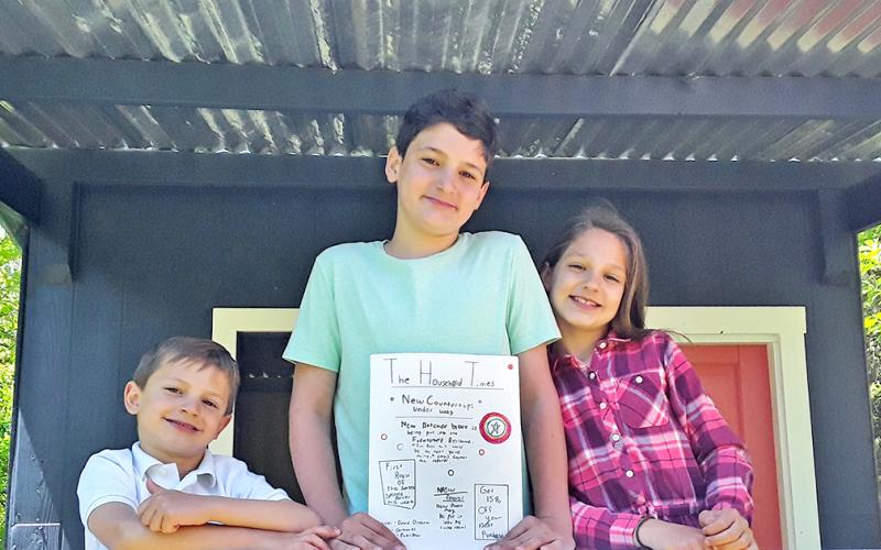 Junior journalists pictured (from left) Benjamin, Samuel, and Abigail Fuerstenberg show off the latest edition of The Household Times, the siblings' own homemade newspaper, made each week for their parents.