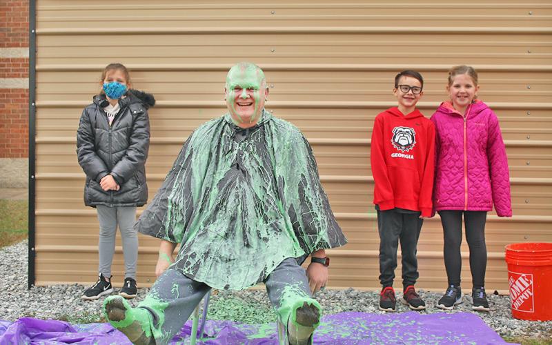 Long Branch SRO Nick Parrish was slimed in celebration of exceeding the school's original fundraising goal, much to the pleasure of LBES students (from left) Ellie Flynt, Micah Smith and Briley Seabolt.