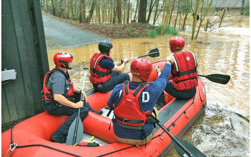 The Lumpkin County Swiftwater Rescue Team, including, from left, Chris Maloney, Derrick Haney, Eric Wimpy and Brennan Powell prepare to launch into the flood swollen waters at Golden Avenue. (Photo courtesy of David Wimpy)