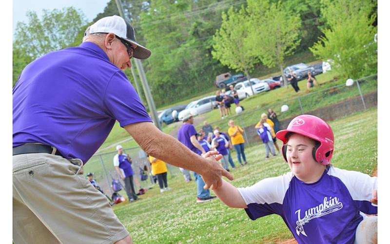Larry Armstrong lends a hand to Delaney Rider after her super slide into home.