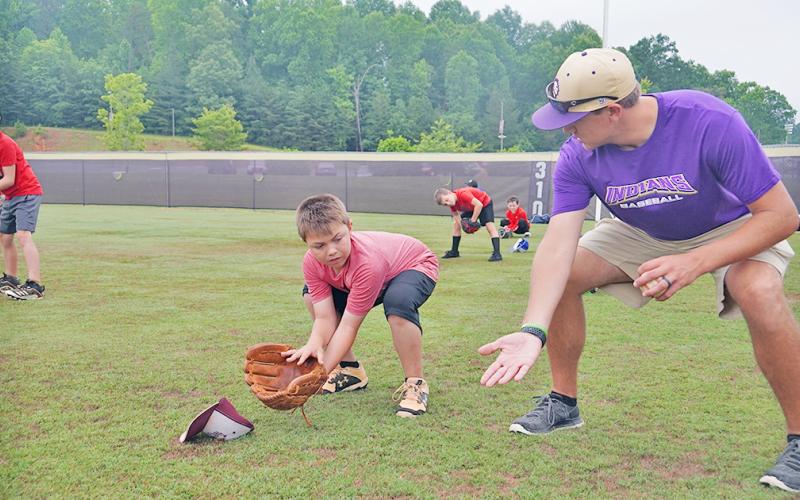 LCHS alum and LCMS Baseball Coach Daniel McCrary (right) shows Kason Dehne the proper ready position as an infielder preparing to field the ball during the Lil’ Indians Baseball Camp held at the high school last week.