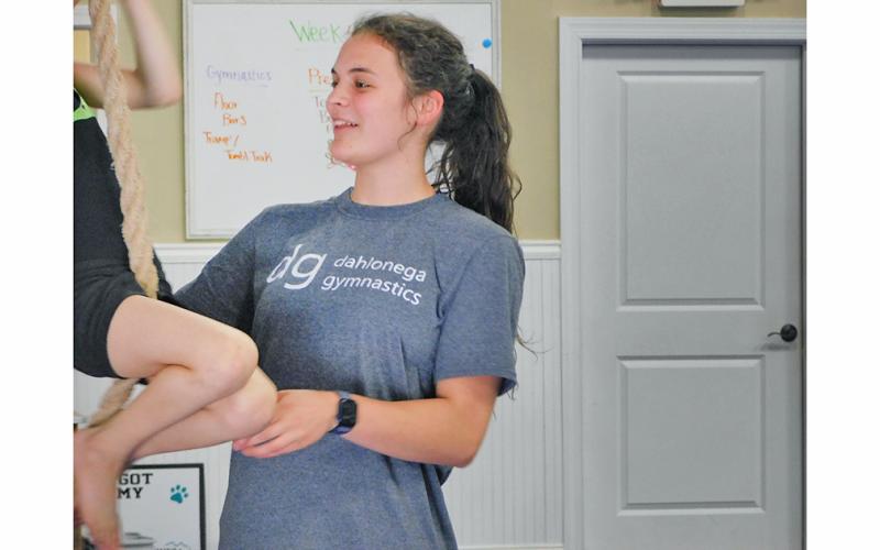 Julia Lancaster helps a student climb a rope at Dahlonega School of Gymnastics, where she teaches 5 and 6 year olds.