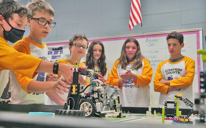 The members of the LCMS LEGO's team watch as Mathieu Weber (left) makes adjustments to the team's robot as it completes tasks as it did when the team won the FIRST LEGO League Tennessee Valley/North Georgia Region Championship in April.