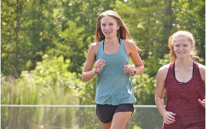 Abbie Hilchie (left) and Kelly Cronan, get warmed up during a recent practice. Hilchie led the way for the girls during their first meet on Thursday, taking fifth overall with a time of 23:15 to help push her team to fourth place at the meet.
