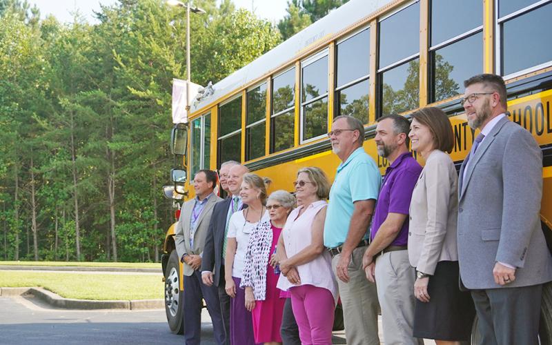 Members of the Board of Education and Central Office staff pose for a photo with one of the system's new buses.
