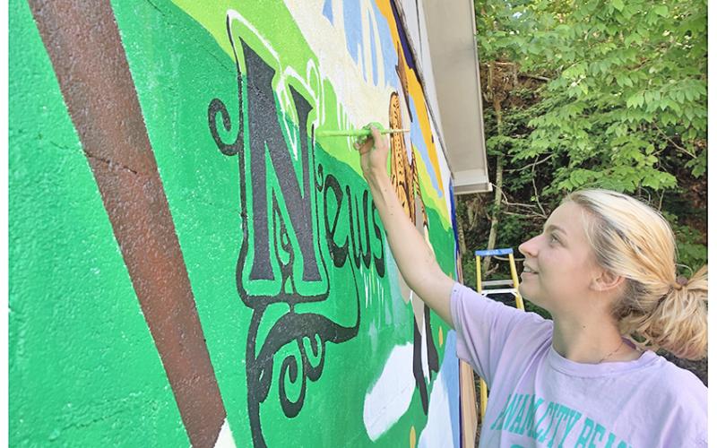 Whitney Little works diligently on the new mural that now decorates the side of The Nugget office.