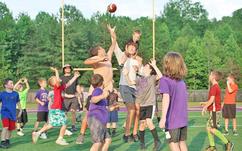 With a camper on his back, LCHS Football player Walker Scott looks to provide an assist to the group of first and second graders on his team during the LCHS Youth Football Camp last week.