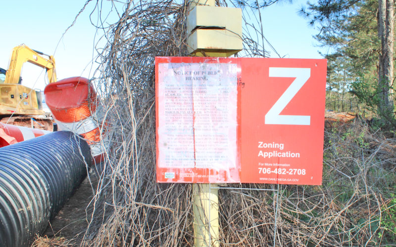 A sign advertising the March 7 meeting of the City Planning Commission stands at the end of Pinetree Way. Residents showed up to the hearing to express their skepticism of the project, which would include a 325-unit apartment complex and 10,000 feet of commercial space.