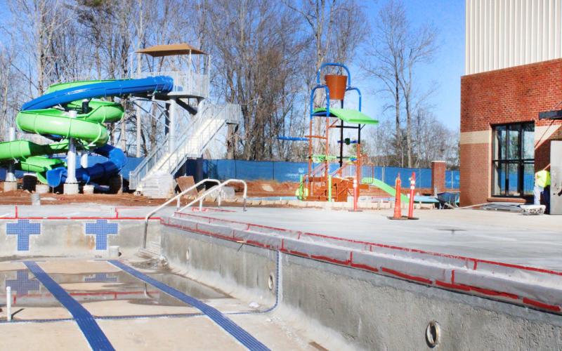 Crews with Carroll Daniel Construction do some finishing work at the rear of the main building. A fully-automated pump house on the opposite side of the competition pool will treat and distribute the swimming water for the entire facility.