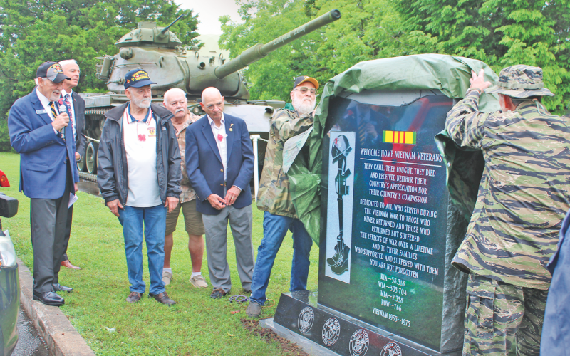 Veterans Hal Williams (left) and Chuck Windham peel back a camouflage covering to reveal the new Vietnam Memorial monument.