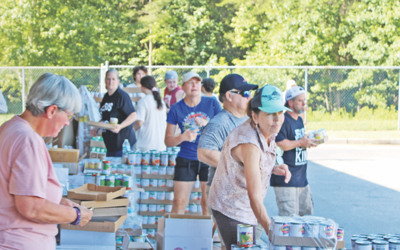 Volunteers organize cans of food and prepare to load them into waiting vehicles at the Unseen Hand Ministry mobile pantry at the parking lot of Blackburn Elementary School in Dahlonega.
