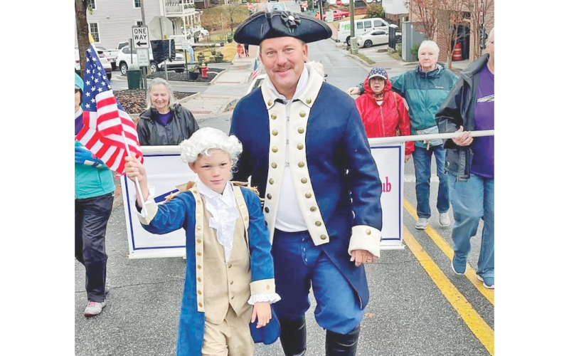Jim Guy and his son Beau march their way towards the square in the Veterans Day parade. This July 4, Jim will return to the Public Square, in colonial attire, to read the Declaration of Independence.