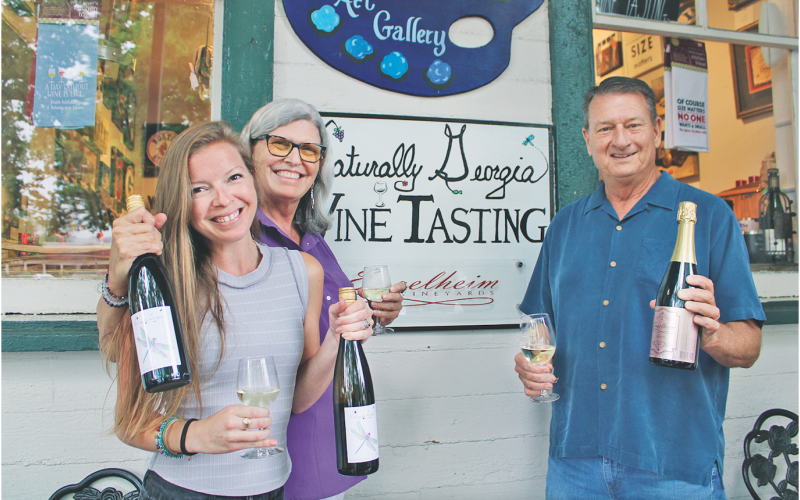 Naturally Georgia manager Amanda Holt (left) and owner Vickie Cooper show off bottles of their proprietary Dragonfly White, while Engelheim Vineyards owner Gary Engel displays his new sparkling Glitzern.