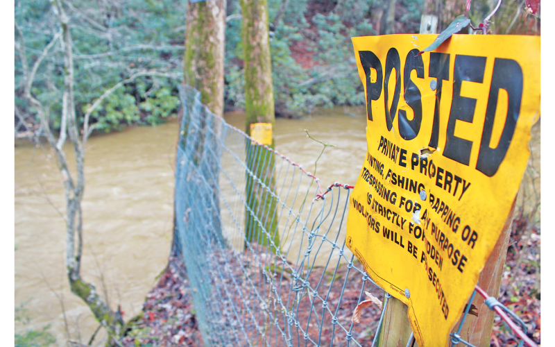 “No trespassing” signs delineate private property near the Etowah River bridge on Ga. Hwy. 52, a popular put-in spot for local floaters and paddlers. The Etowah is not technically considered navigable, so its waters could be restricted if the property on both sides is marked private.