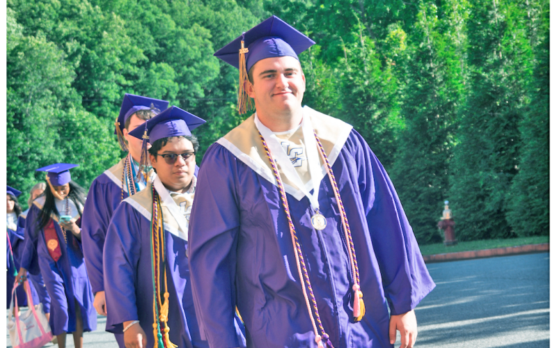 Senior member of the football team, Matthew Reece, smiles in his graduation cap and gown as he and his classmates prepare for commencement.