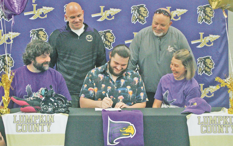 Hayden Roy is set to continue his wrestling career at Hunter College in New York City. Pictured: Roy signs his official commitment surrounded by his parents and coaches.