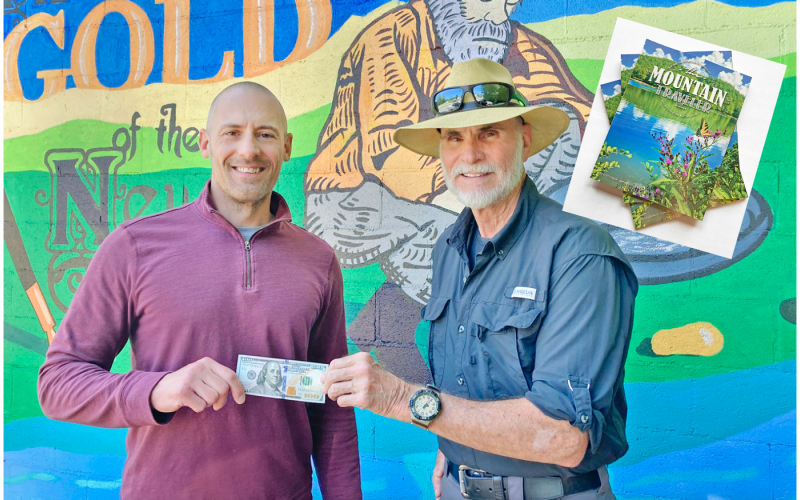 The Dahlonega Nugget Publisher John Bynum (left) presents the $100 prize to local resident Bill Perdue for his winning photo. Perdue captured the photo for the cover of the summer edition of The Mountain Traveler magazine.