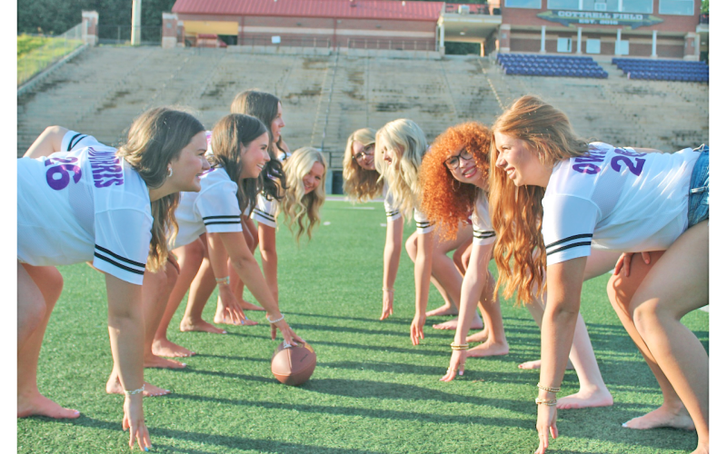 The Lumpkin senior cheerleaders spend a lighthearted moment channeling their inner football players as the offensive and defensive lines would line up during a game on Friday Night.