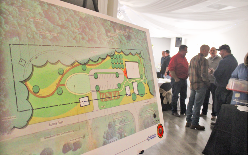 A concept plan depicts a restored Woody’s Store and Kate Woody Building facing Auraria Road, with the addition of a new 8,000 square foot museum and outdoor amphitheater behind them.