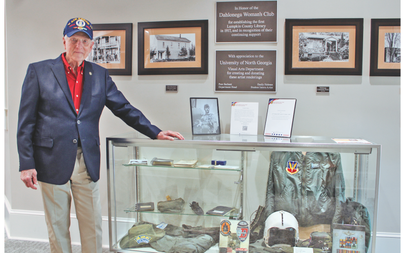 LTC Colonel (RET) Lewis “Lew” M. Houser is currently featured in a rotating exhibit at the Lumpkin County Library called “Outpost Alpha,” which honors local veterans. Here, he stands next to a glass case displaying Vietnam-era military memorabilia, including his Air Force flight jacket, helmet, gloves and service medals.