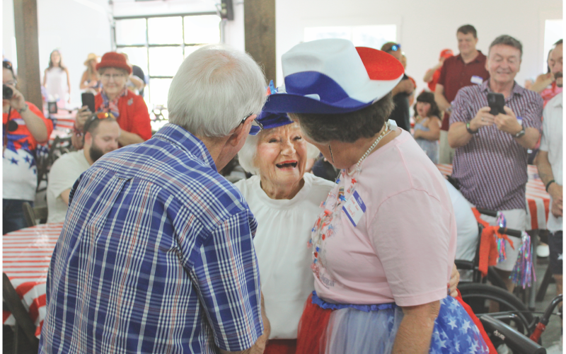 Emma “Queen” Jean Jarrard, center, is greeted by friends during her centenary birthday celebration at Wimpy Farms in Dahlonega. Jarrard turned 100 on July 4, as the nation celebrated its 250th birthday.