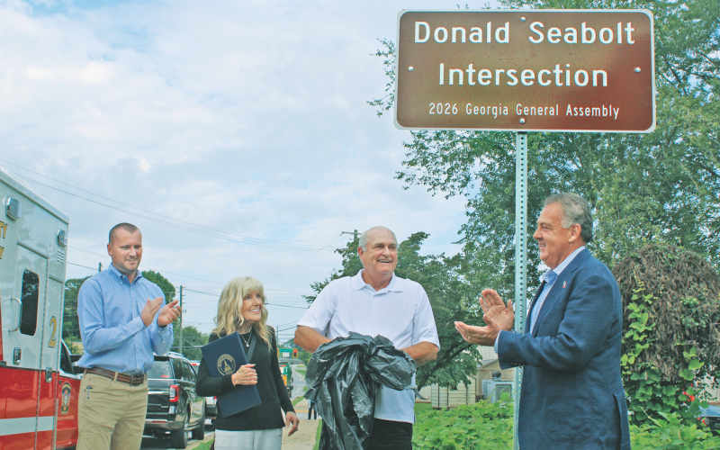 Retired Dahlonega-Lumpkin County Emergency Management Agency Director Donald Seabolt was all smiles Monday as a new sign was unveiled declaring the intersection of Pinetree Way and Morrison Moore Parkway the “Donald Seabolt Intersection.” Pictured from left are County Chairman Rhett Stringer, Gail Seabolt, Donald Seabolt and State Senator Steve Gooch.