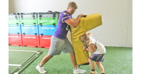 LCHS football player Aaron Hopkins teaches a camper the proper way to drive an opponent backwards during a drill.