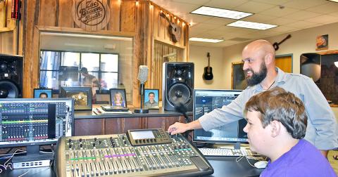 Music teacher Radford Windham shows student Brendan Diehl some of the many functions of a soundboard, purchased with money donated by Mike and Lynn Cottrell.
