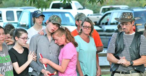 Austin Bender holds a candle in honor of his sister as he consoles his mother Carol Gillreath at last week’s vigil on Lake Zwerner.
