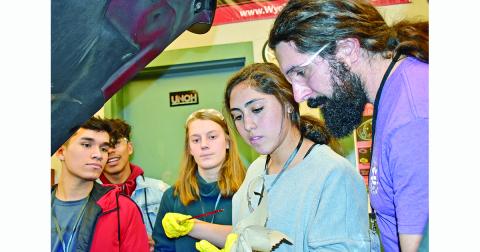 Jesse Perethian, LCHS graduate and now a bus driver for the school system, instructs Hope Kenney on how to check the oil in a vehicle while fellow students look on. This was just one of the lessons learned at the auto maintenance station during Senior Adulting Day.