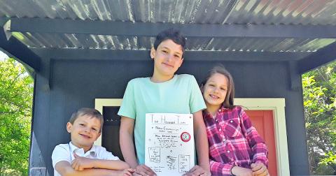 Junior journalists pictured (from left) Benjamin, Samuel, and Abigail Fuerstenberg show off the latest edition of The Household Times, the siblings' own homemade newspaper, made each week for their parents. 
