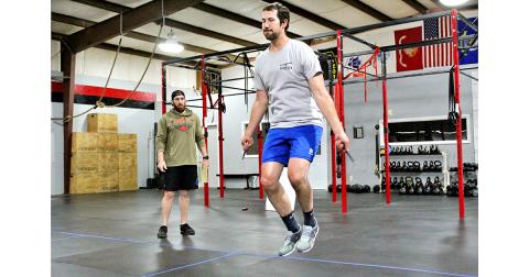 Jordan Meeks jumps rope during a workout at CrossFit Dahlonega as trainer and gym owner Thomas Coggins oversees the session.