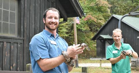Environmental Education Programs Coordinator Adam Rolwes holds an Eastern King Snake while Center Director David Weber holds an Eastern Box Turtle, which are some of the reptiles that visitors can interact with and learn about.