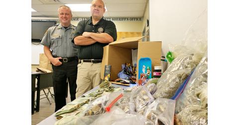 Sheriff Stacy Jarrard and Captain Marcus Sewell stand beside a table full of evidence confiscated from a recent drug bust.
